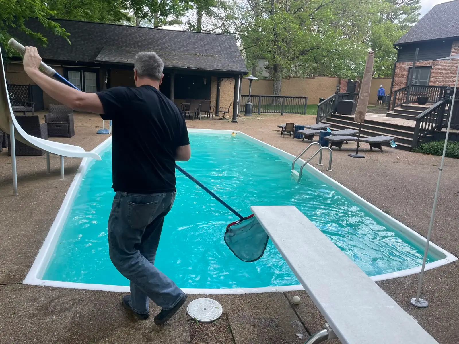Passion Pool Care technician skimming a pool during weekly pool cleaning
